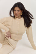 Cream shaping cardigan designed to flatter the waist and frame the neckline.
