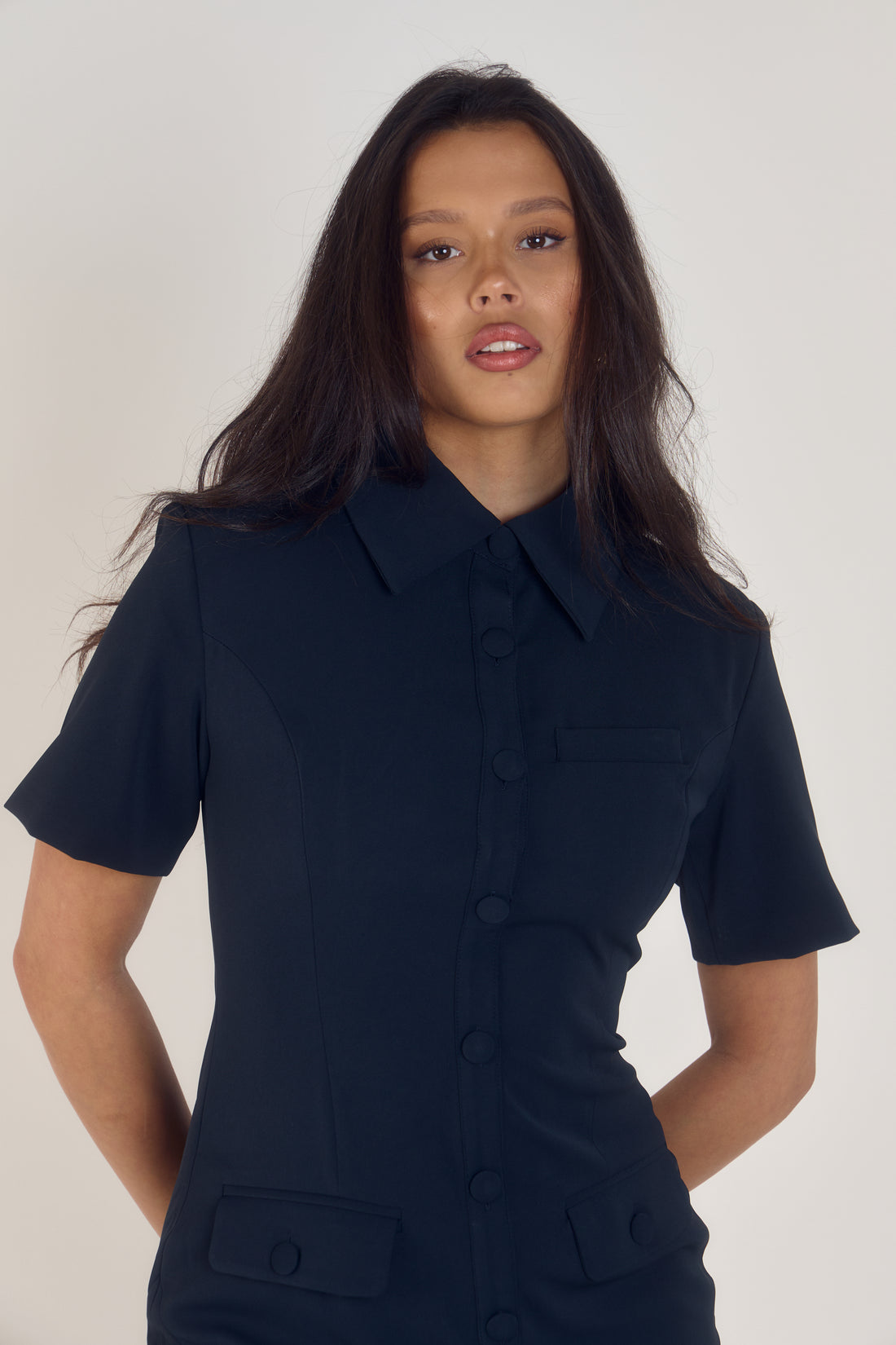 Ardore London Sculpting Short Sleeve Buttoned Knee Length Dress in Midnight Bleu, offering a polished, office-ready look with flattering curved seams, structured collar, and functional pockets for a sleek, professional appearance