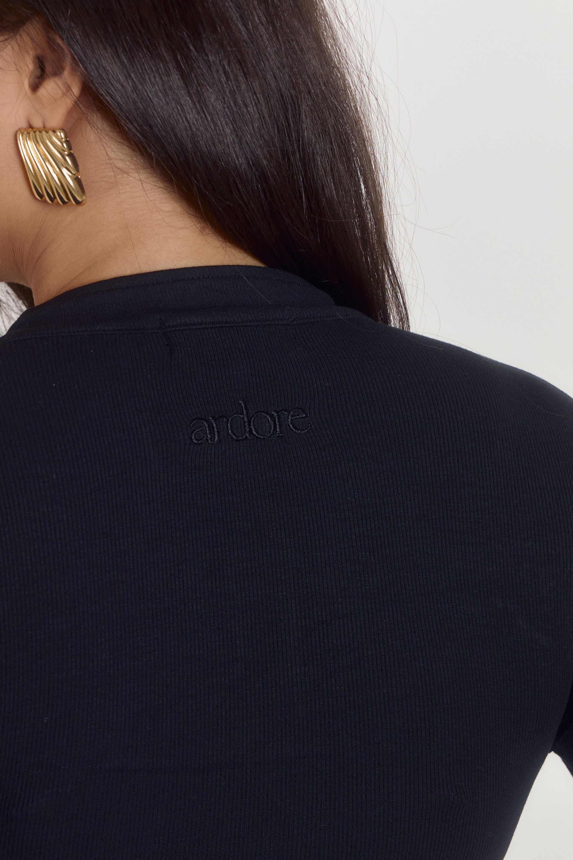 Soft black cotton ribbed bodysuit with polished elevated neckline.