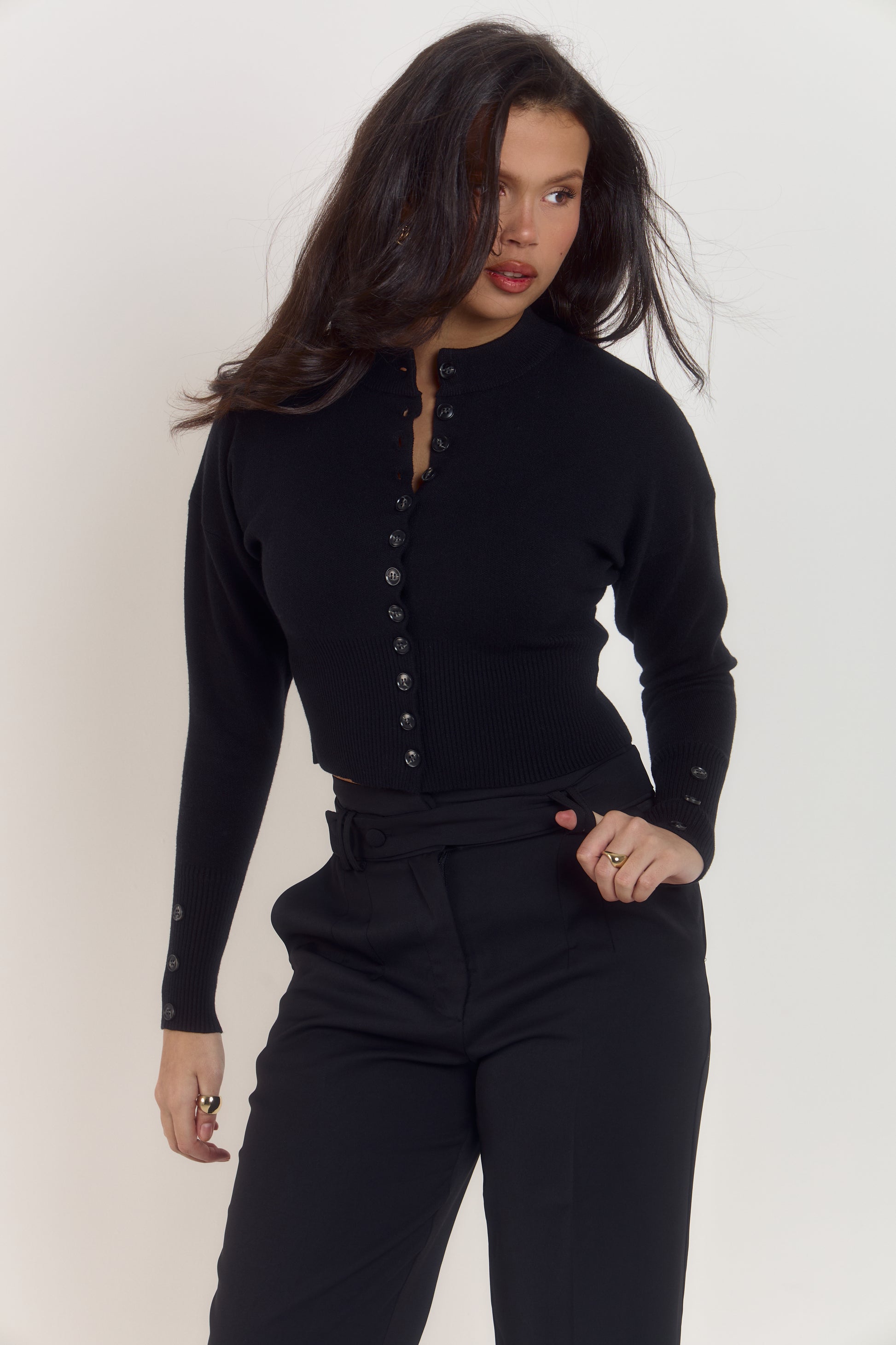 Mid-length black sculpting waist cardigan with elegant movement and triple button cuff feature.