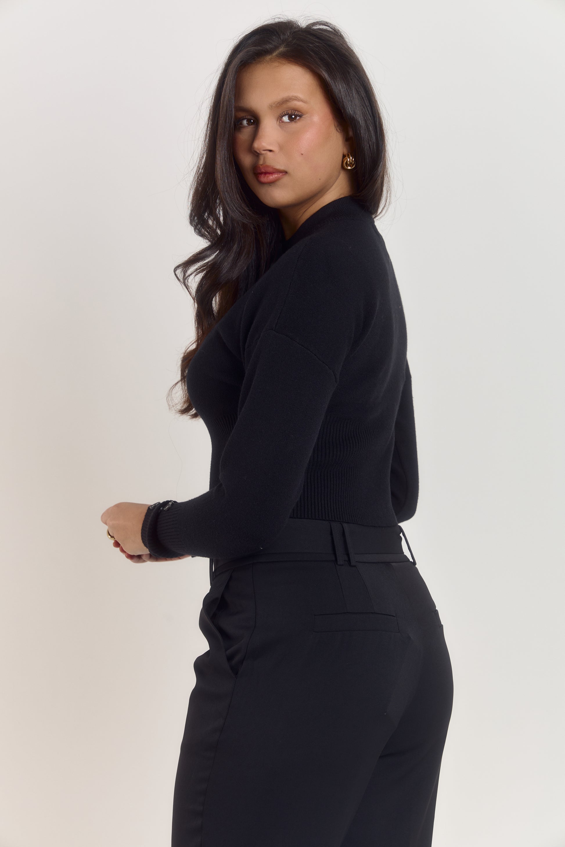 Women’s fitted black cardigan with waist sculpting design, high rounded collar and triple button cuff detail.