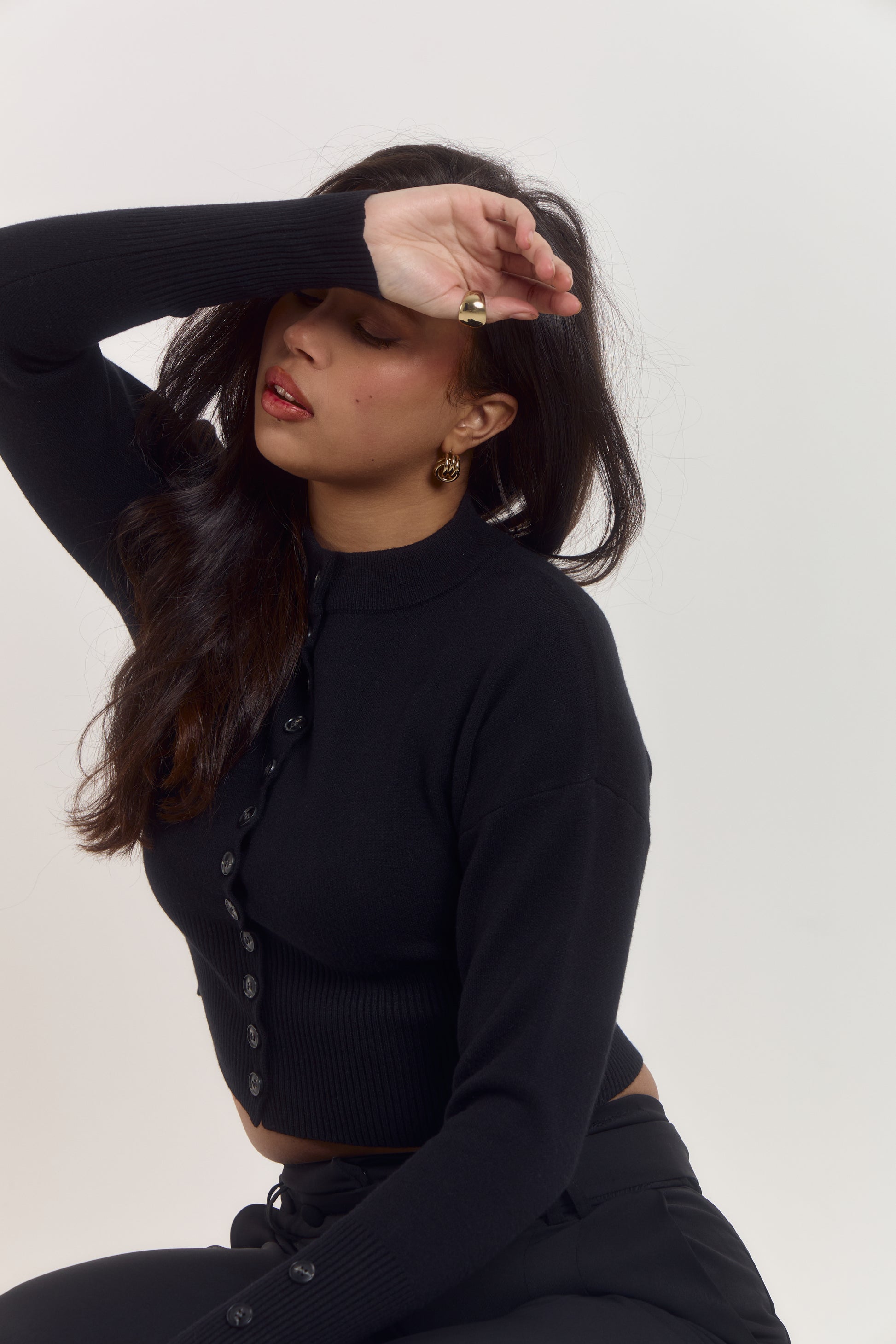 Mid-length black sculpting cardigan with high rounded collar and triple button cuff detail.