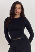 Close up of structured black shapewear bodysuit fabric with smoothing compression and subtle logo detail.