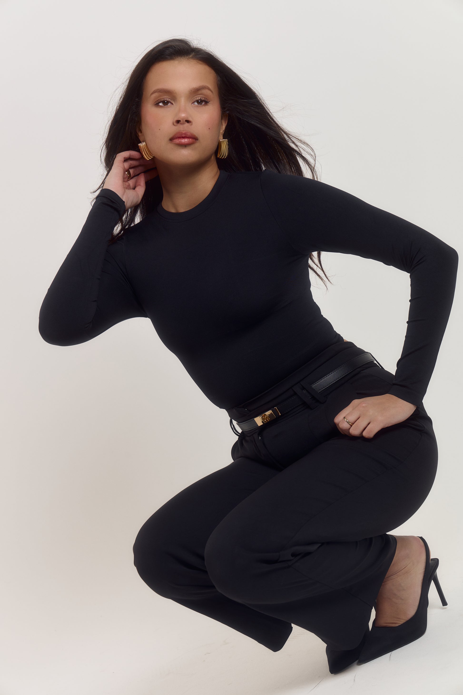 Fitted black shapewear bodysuit with waist defining compression zone and adjustable popper closure.