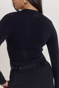 Model wearing black long sleeve shapewear bodysuit with waist compression zone and sculpting contour fit.