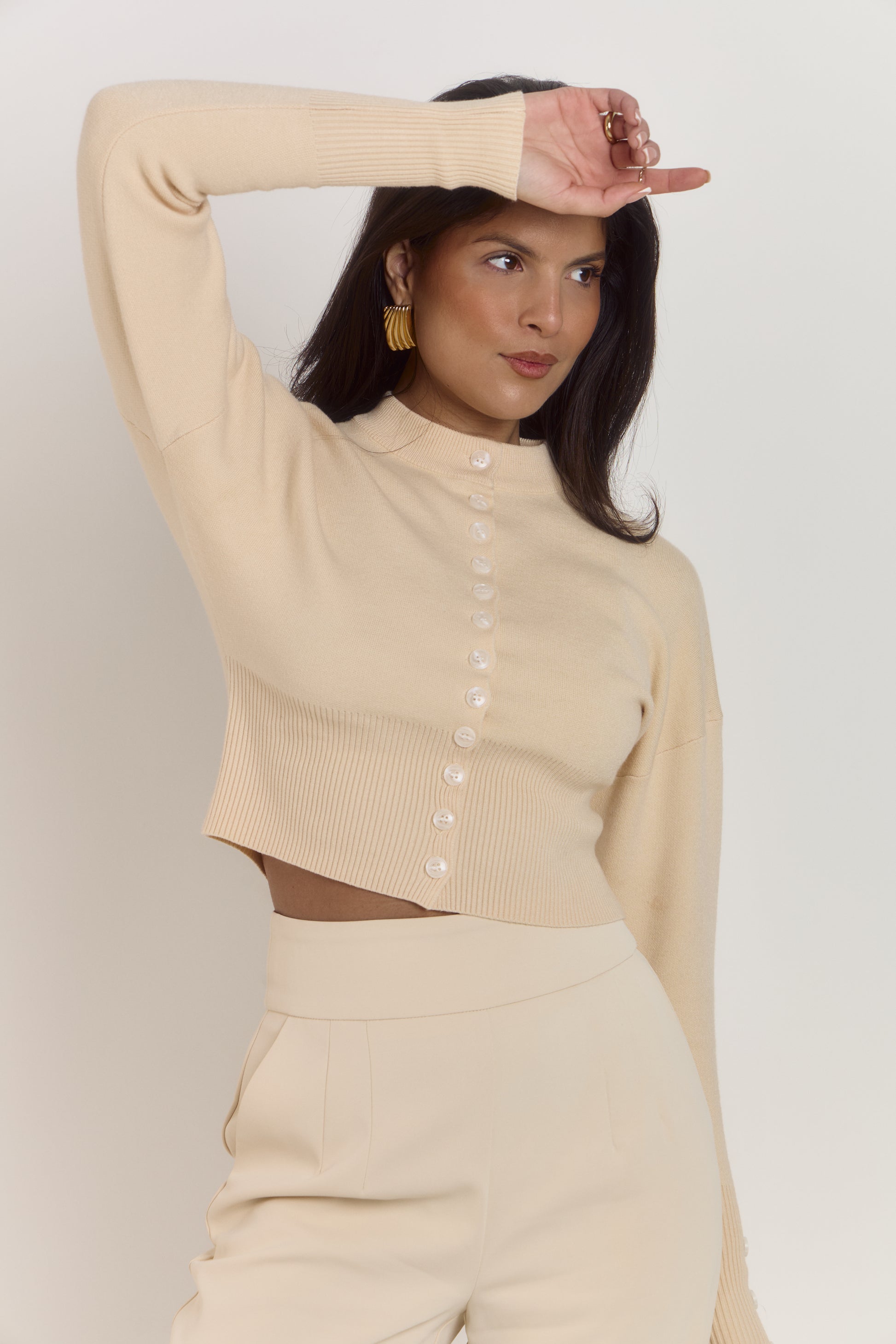 Cream structured cardigan with button front closure designed to prevent gaping.