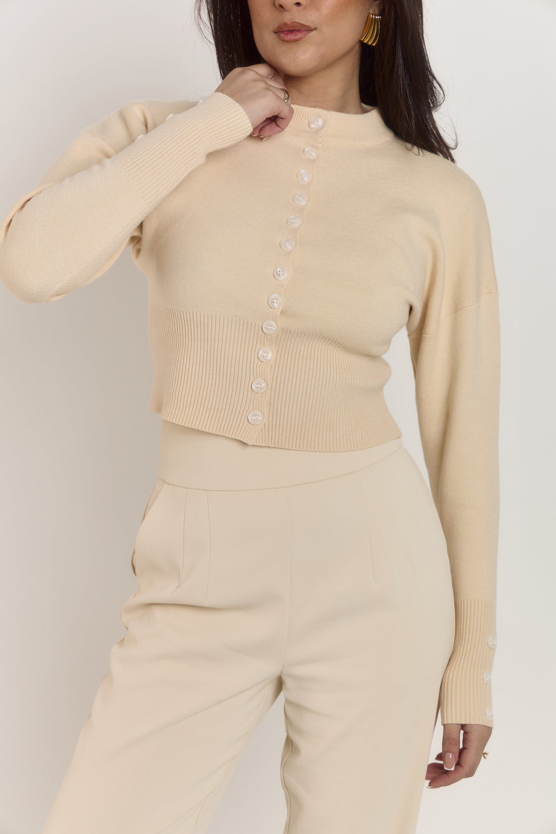 Cream structured cardigan with button front closure designed to prevent gaping.