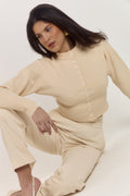 Elegant cream cardigan with fitted waist and softly structured silhouette.
