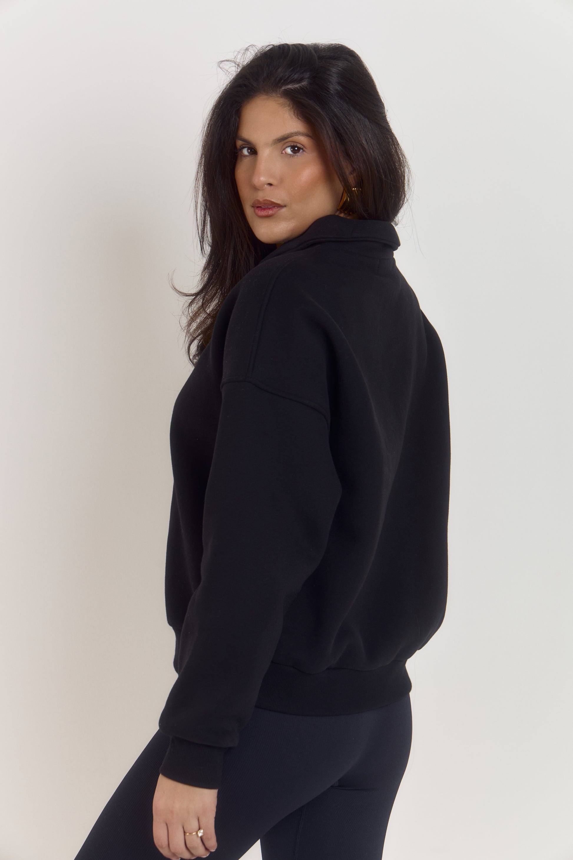 Close-up detail of black cotton oversized collared sweater with quarter button closure and premium structured fabric.