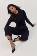 Model styled in black long sleeve shapewear bodysuit layered under tailored blazer for smart casual look.