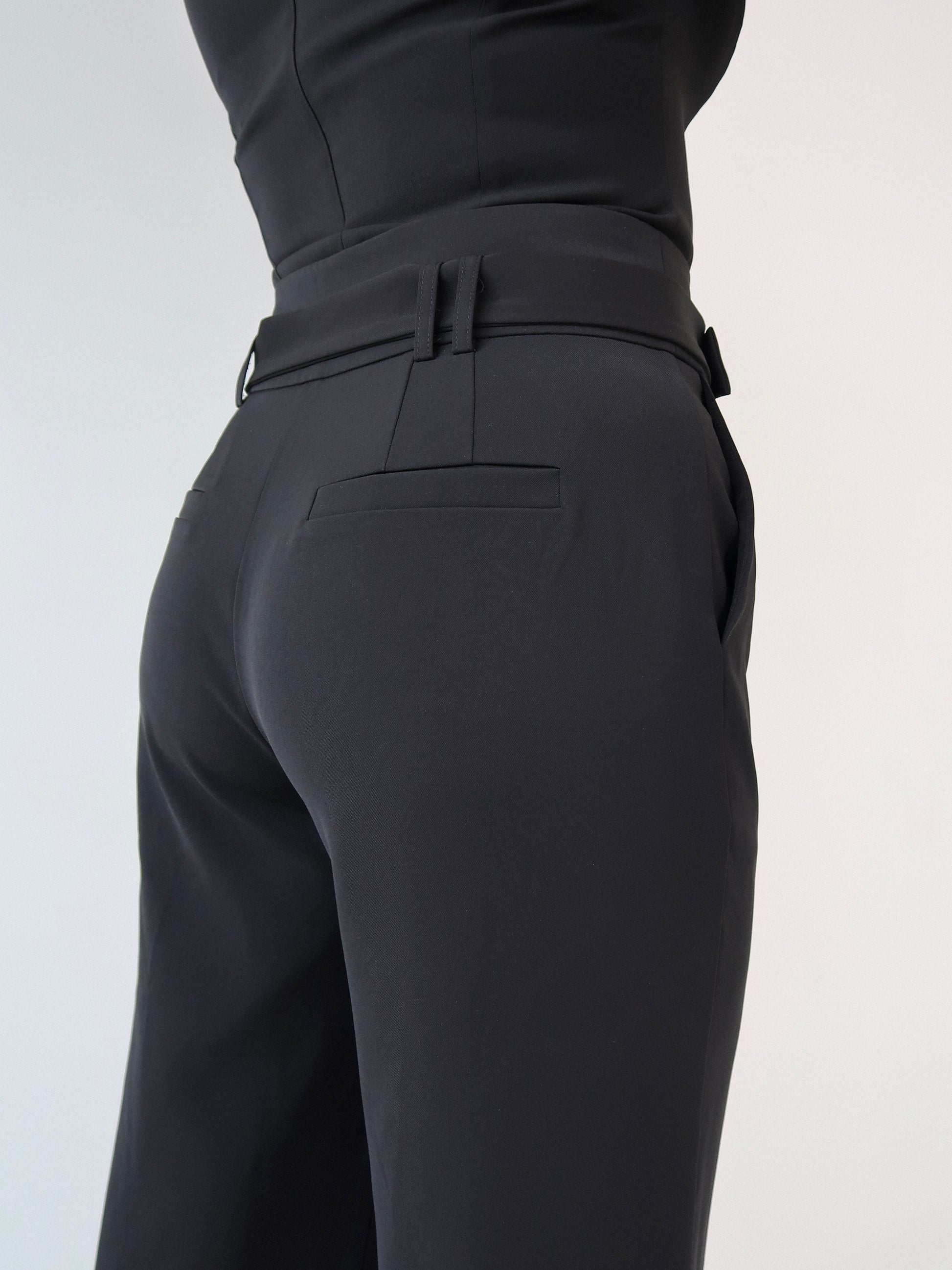 Side view of black tailoring belted wide leg trousers in Classic Noire by Ardore London, highlighting the structured high-waist fit, flowing side drape, and refined tailoring details.