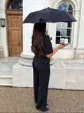 Side view of black tailoring belted wide leg trousers in Classic Noire by Ardore London, designed with a high-rise fit and fluid wide-leg silhouette — a modern workwear essential for effortless office elegance.