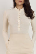 Soft cotton ribbed buttoned bodysuit in vanilla with flattering slim fit shape.