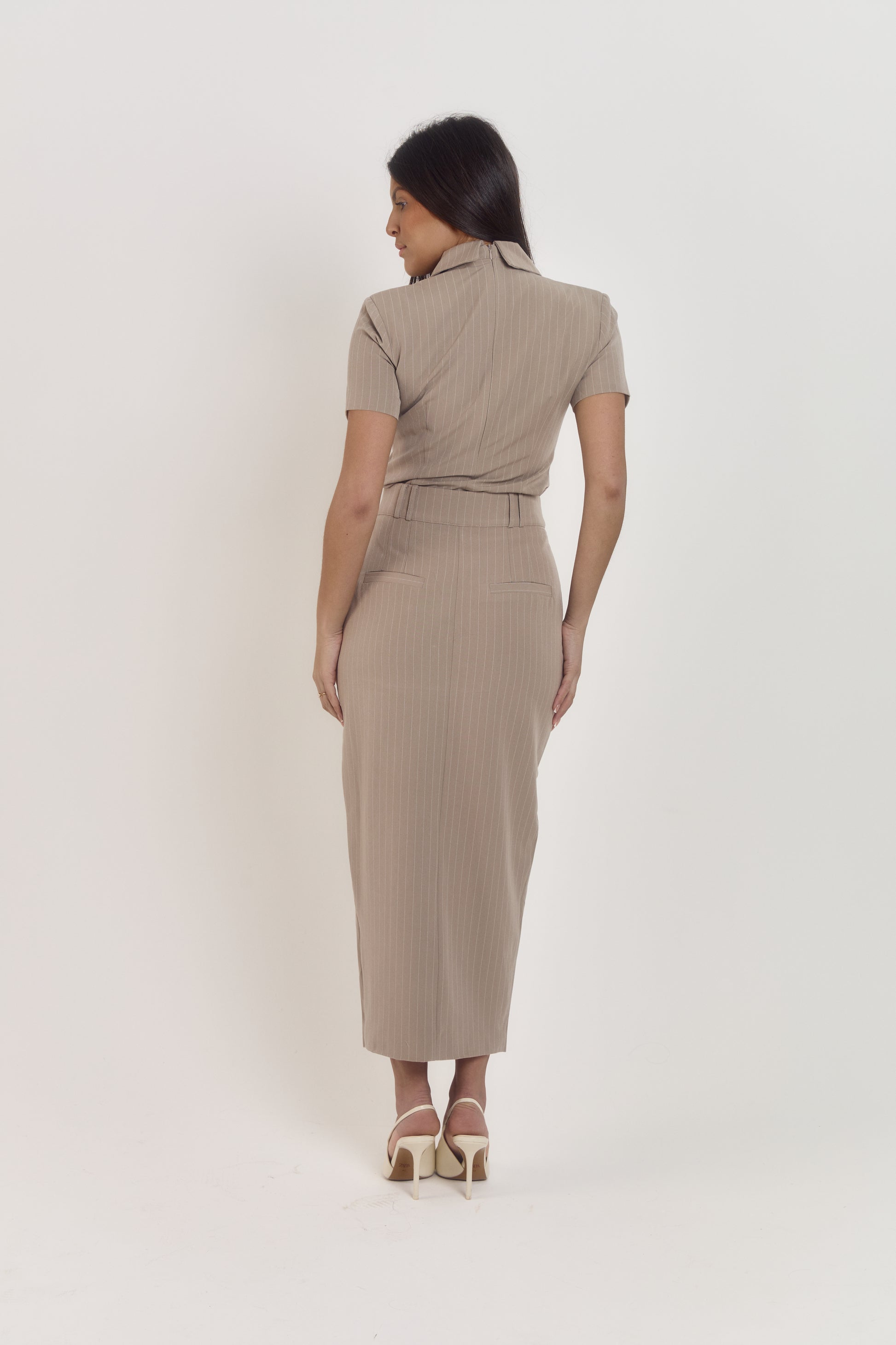 Model wearing taupe pinstripe polo blouse and matching midi skirt, elegant office ready two-piece set.