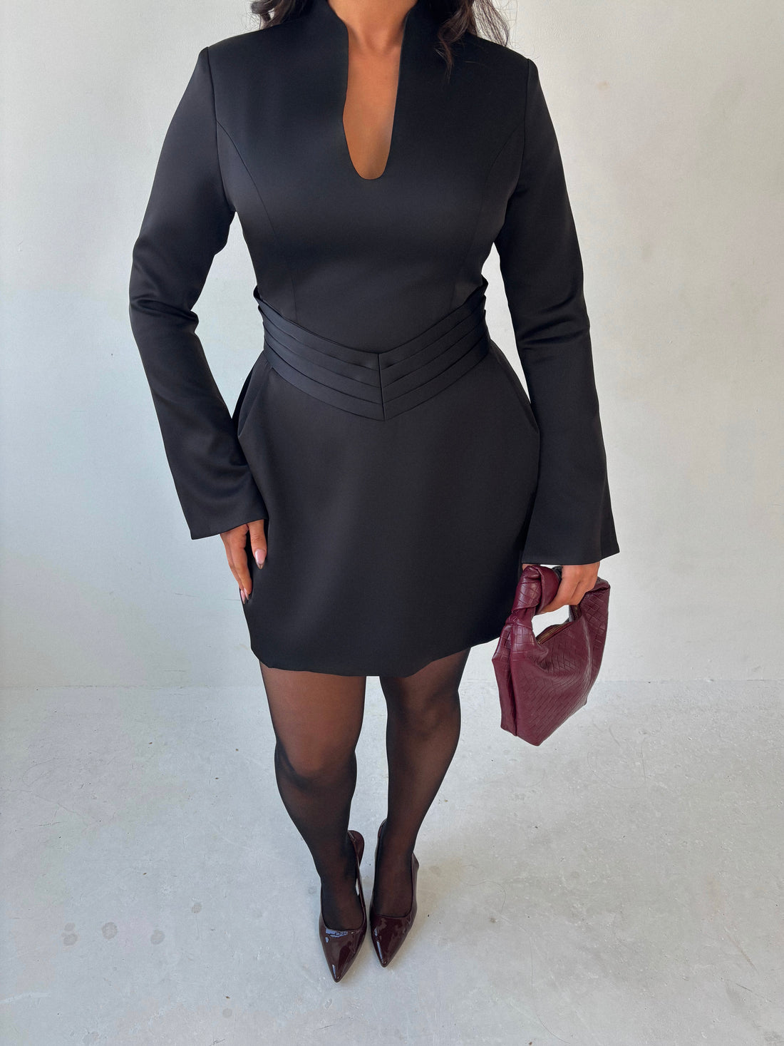 Close-up of Ardore London black satin split sleeve mini dress, featuring a pleated V-shaped waist for a flattering fit, an elegant A-line skirt, and fluid split sleeves—crafted in lustrous satin for a sleek winter-ready silhouette with graceful movement and modern edge.