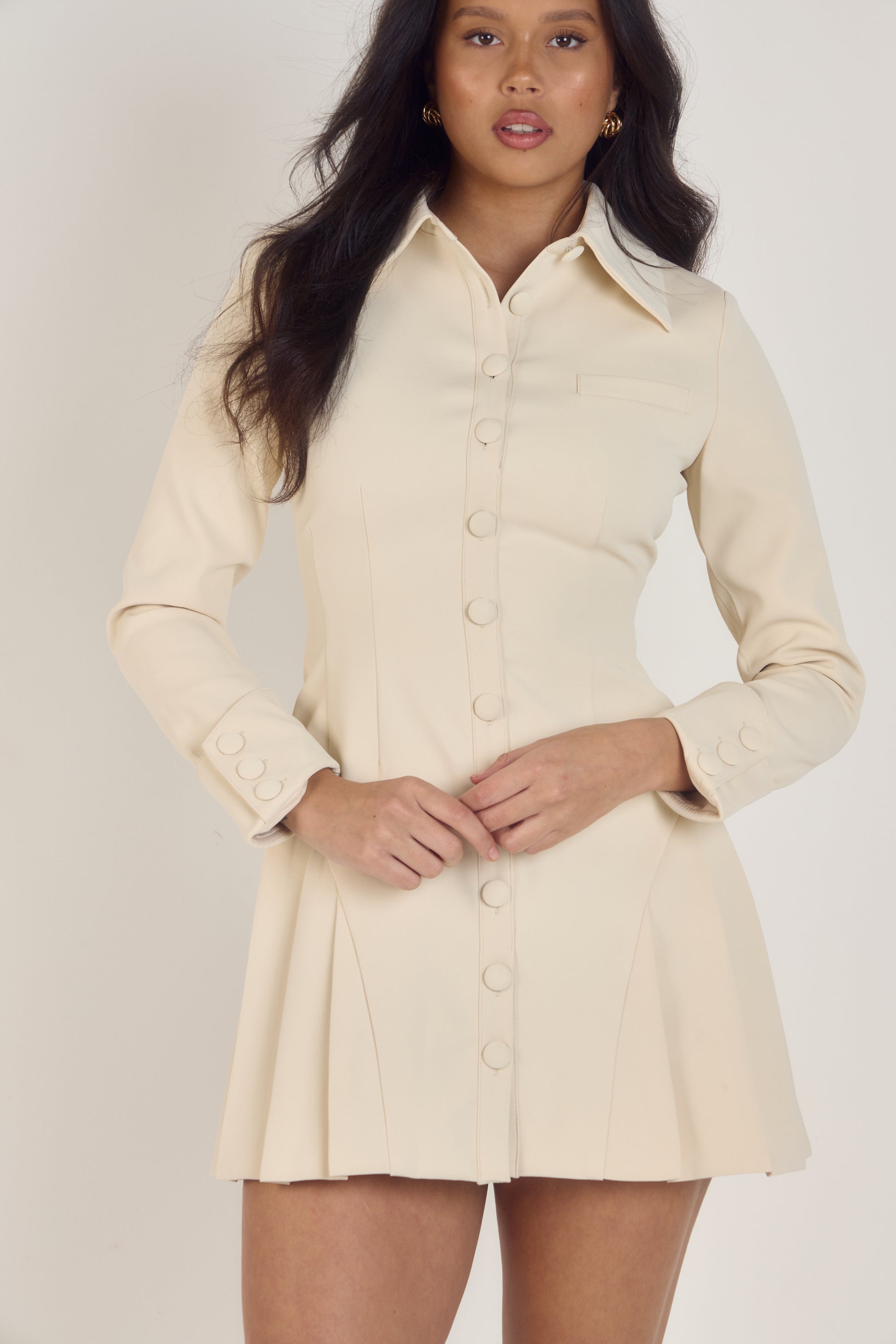 Ardore London Vanilla Crème structured long sleeve pleated mini dress, featuring precise tailoring, a textured fabric, and defined sleeve construction—an elegant, cozy choice for winter with its warm tones and full coverage silhouette.