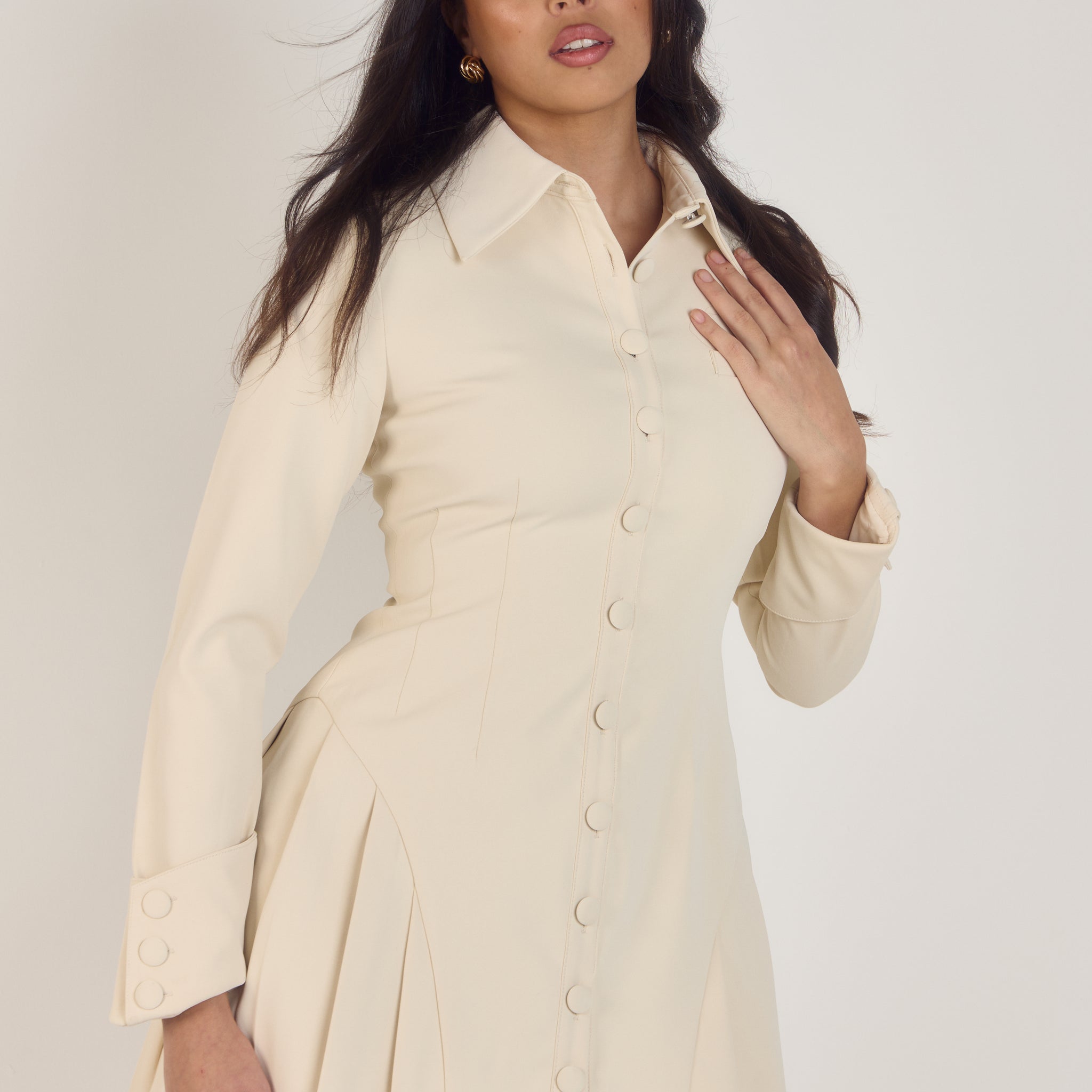 Ardore London Vanilla Crème structured long sleeve pleated mini dress, featuring precise tailoring, a textured fabric, and defined sleeve construction—an elegant, cozy choice for winter with its warm tones and full coverage silhouette.