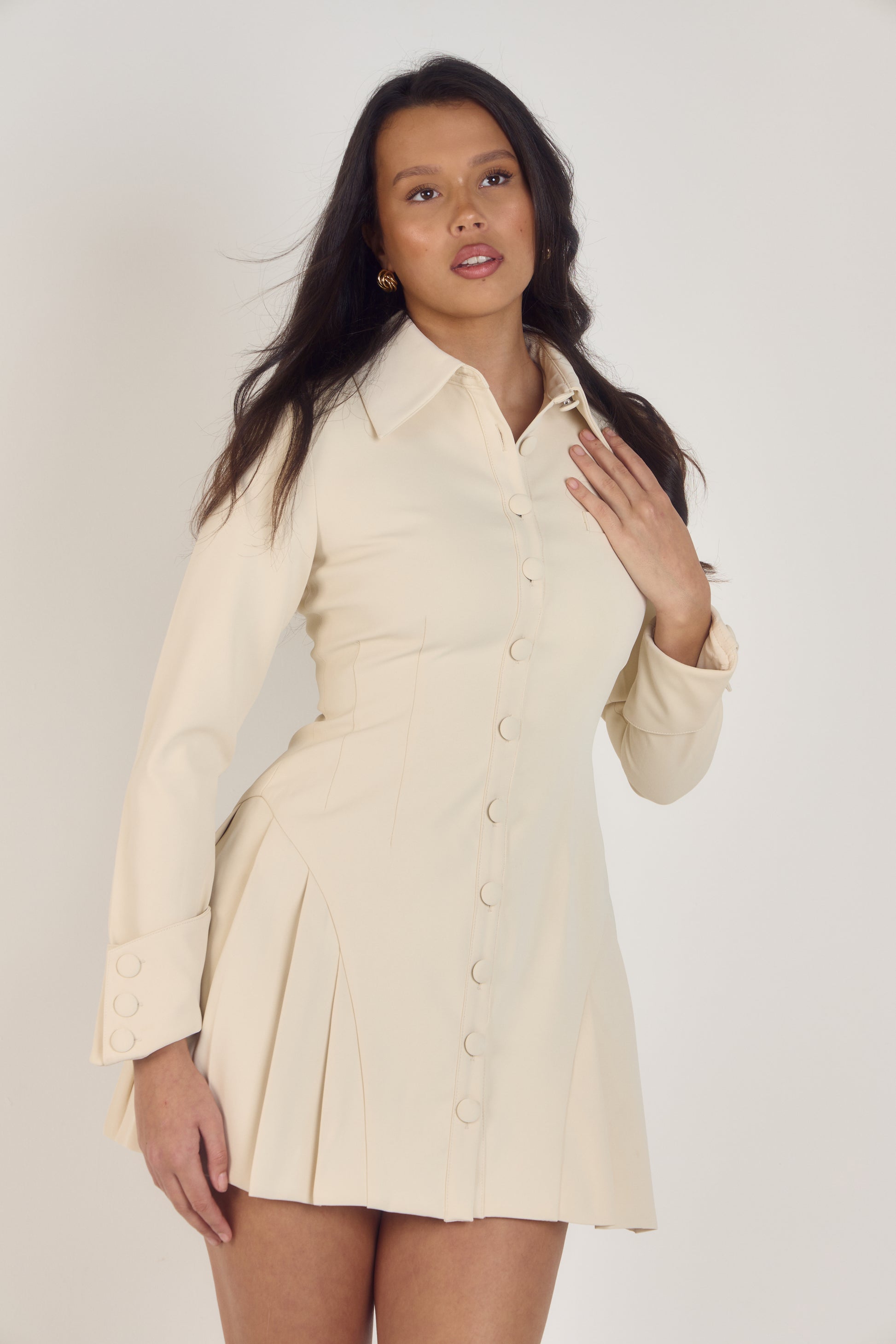 Ardore London Vanilla Crème structured long sleeve pleated mini dress, featuring precise tailoring, a textured fabric, and defined sleeve construction—an elegant, cozy choice for winter with its warm tones and full coverage silhouette.