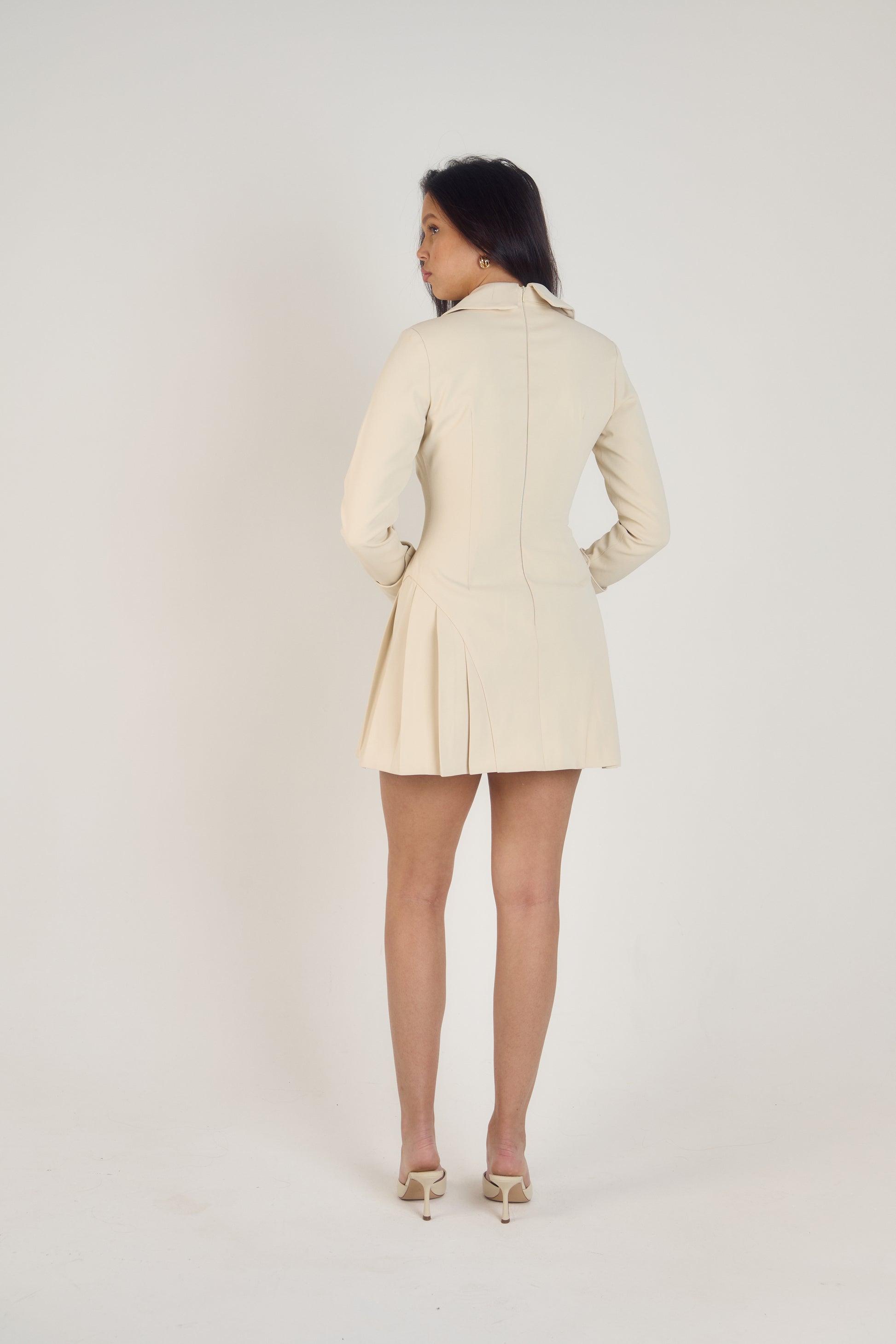 Ardore London Vanilla Crème structured long sleeve pleated mini dress, featuring precise tailoring, a textured fabric, and defined sleeve construction—an elegant, cozy choice for winter with its warm tones and full coverage silhouette.