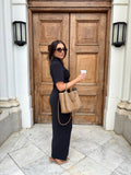 Side view of Ardore London Sculpting Short Sleeve Buttoned Maxi Dress in Classic Noire, styled for a chic office look. Featuring a flattering silhouette, structured collar, and elegant curved seams, this dress exudes sophisticated professionalism.
