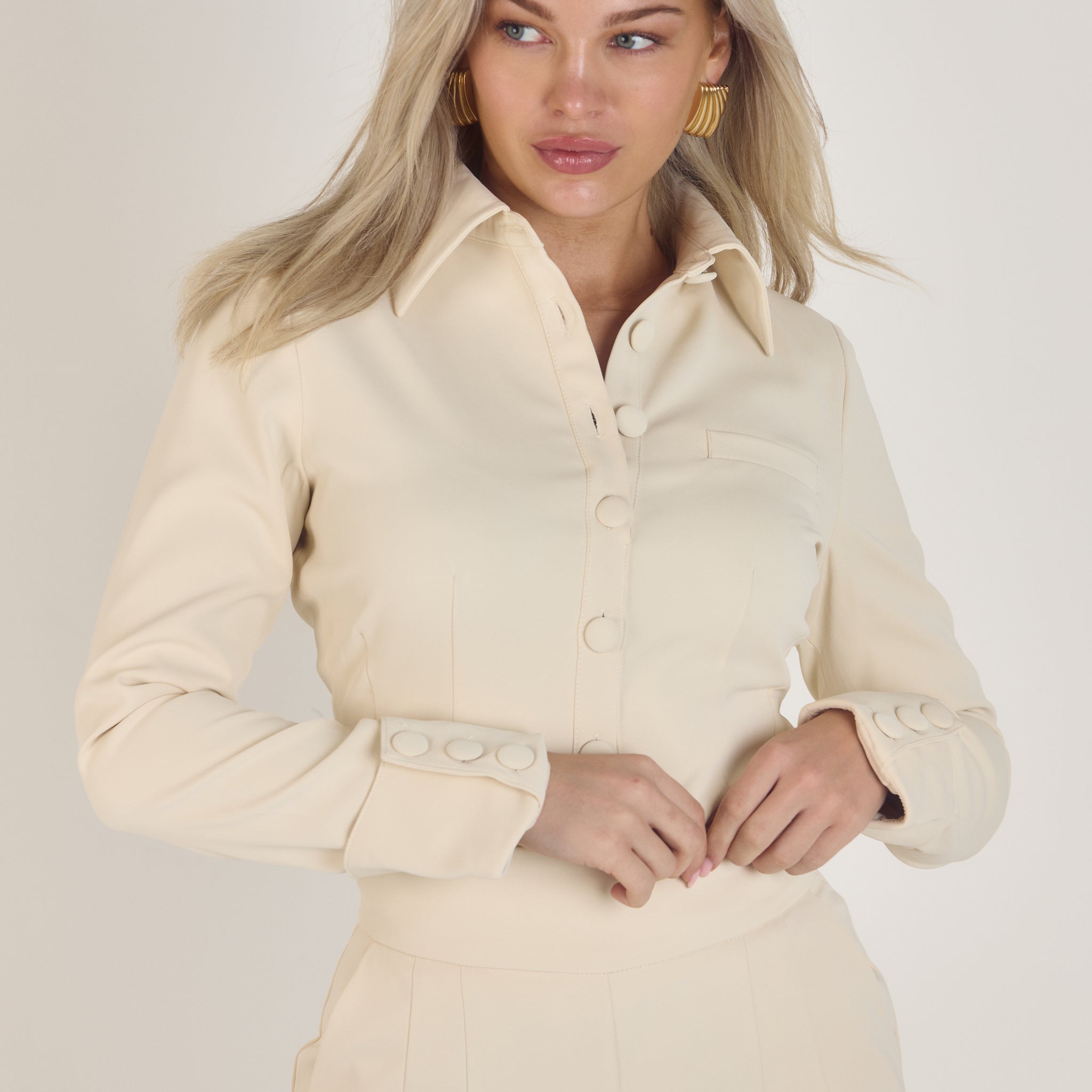 Ardore London Vanilla Crème structured long sleeve sculpted blouse paired with cream trousers, featuring sculpted tailoring, signature triple-button cuffs, exaggerated collar, and soft, luxurious fabric for an elevated, chic look.