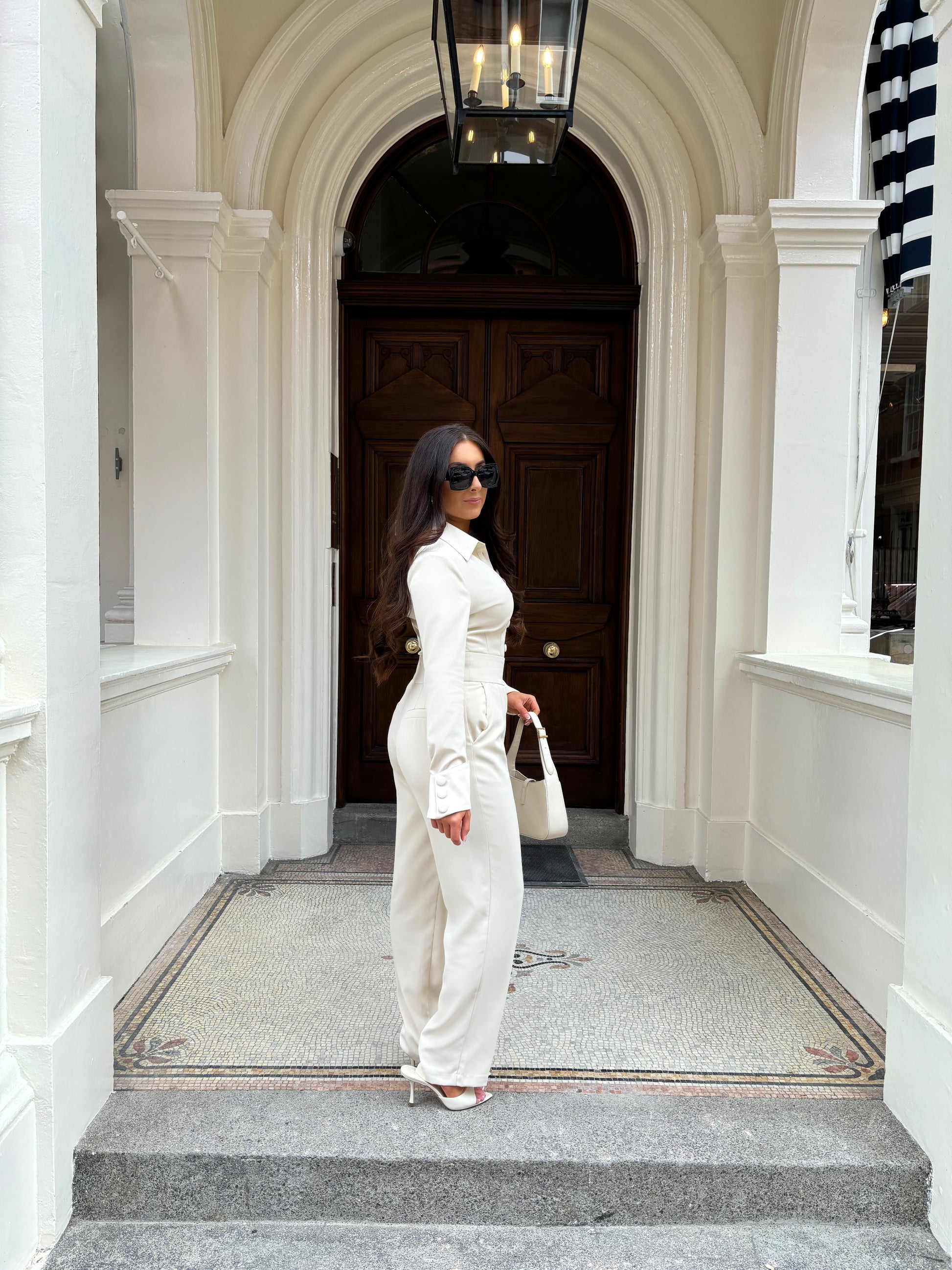 Side view of Ardore London Vanilla Crème structured long sleeve sculpted blouse paired with cream trousers, showcasing sculpted tailoring, signature triple-button cuffs, and an exaggerated collar for a polished, chic silhouette.