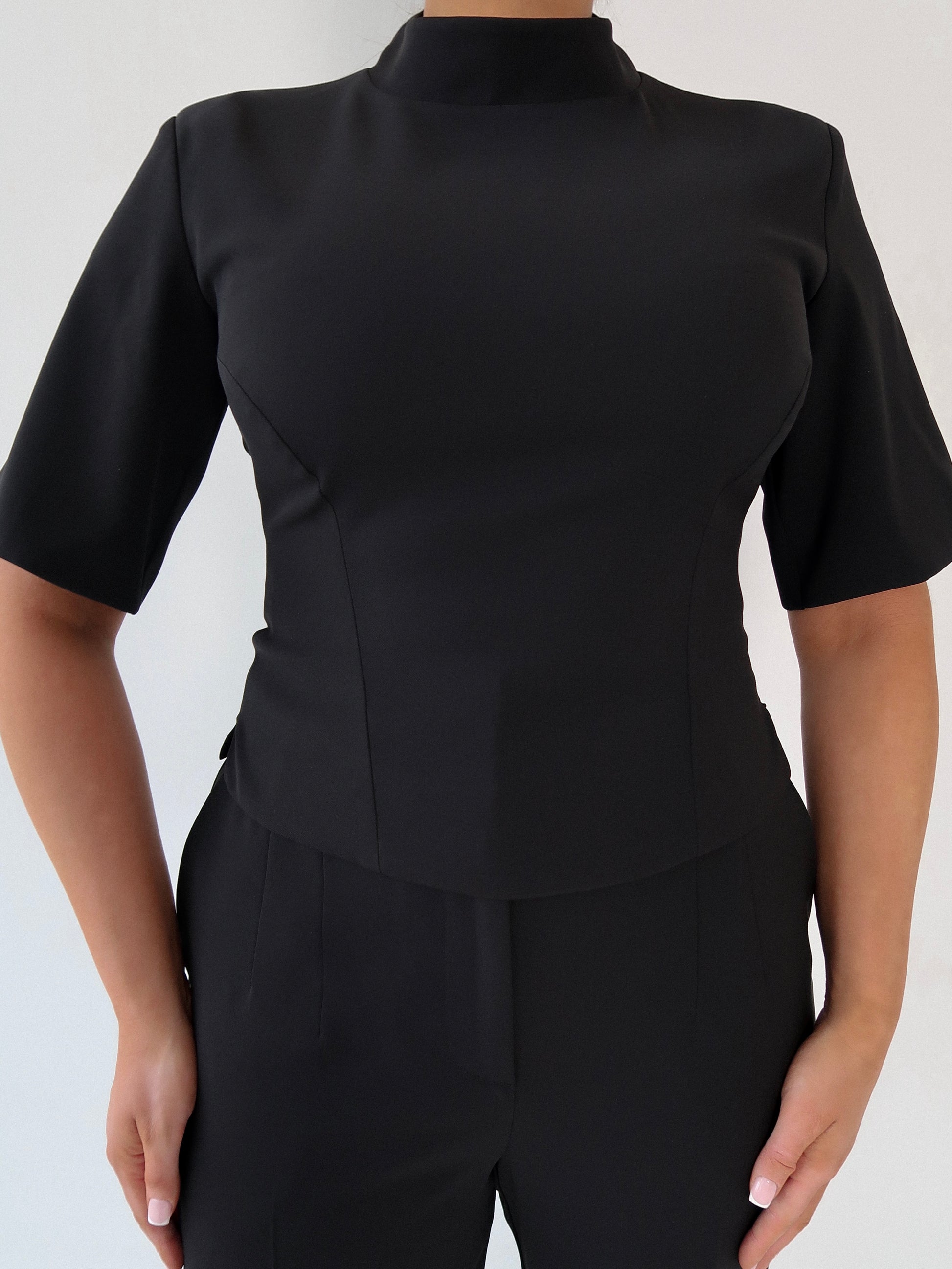 Styled front view of Ardore London’s Tailoring Sculpted High Neck Top in Classic Noire, paired effortlessly for a chic, polished look with wide sleeves and premium fabric