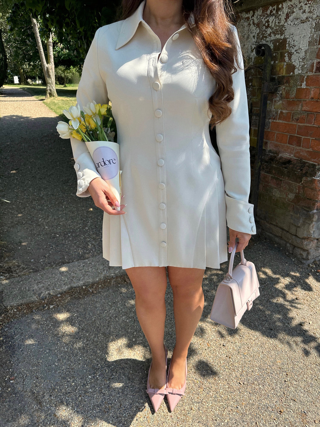 Close-up of Ardore London Vanilla Crème structured long sleeve pleated mini dress showcasing precise tailoring, pleated skirt, textured fabric, and defined sleeve construction.