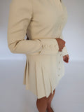 Side shot of Ardore London Vanilla Crème structured mini dress, emphasizing the precise tailoring, pleated skirt, and sculpted sleeve design.