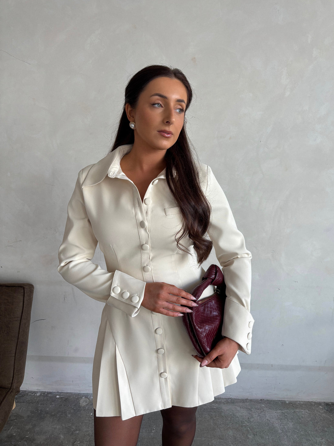 Close-up of Ardore London Vanilla Crème structured long sleeve pleated mini dress, featuring precise tailoring, a textured fabric, and defined sleeve construction—an elegant, cozy choice for winter with its warm tones and full coverage silhouette.